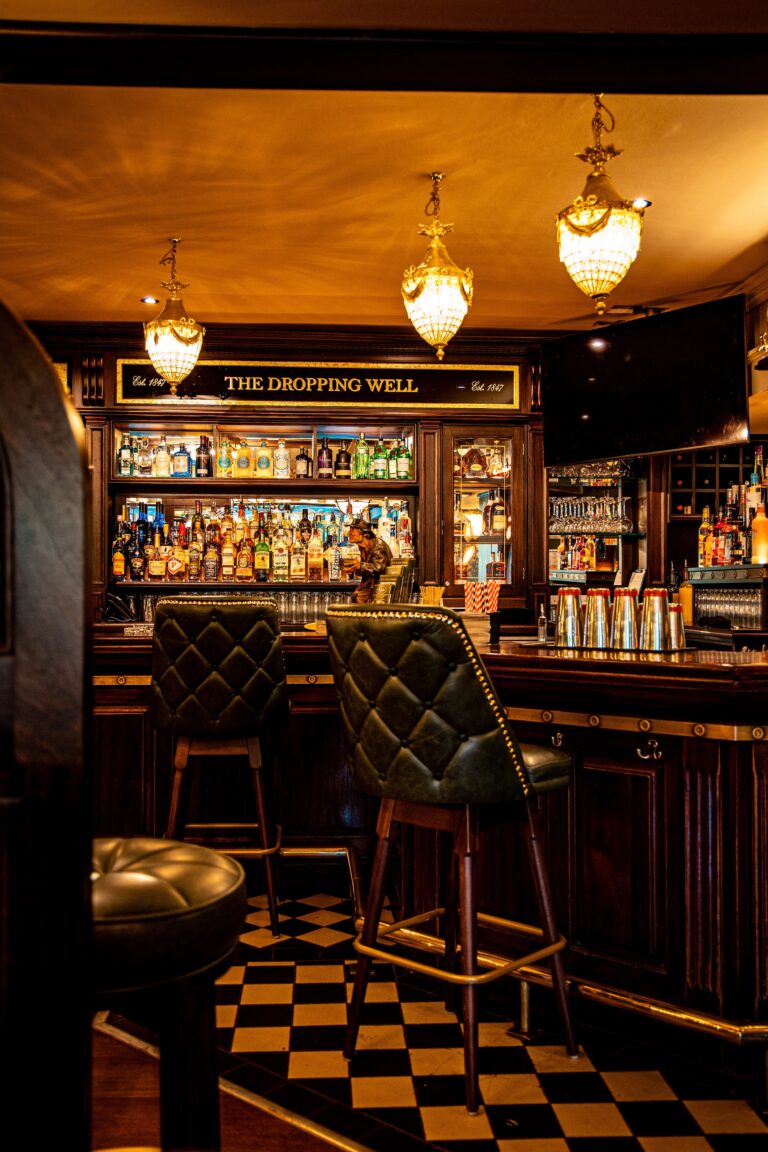 Traditional pub bar with chandeliers and leather stools