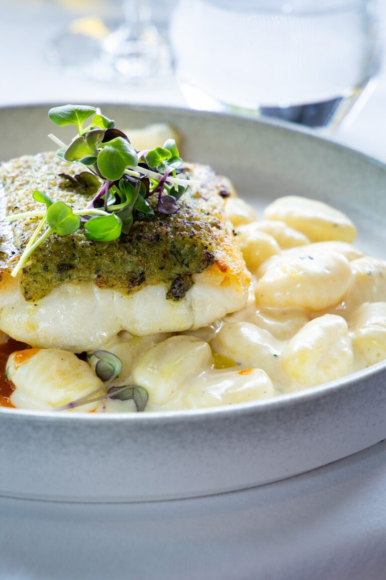 Pesto-crusted fish with creamy gnocchi and microgreens