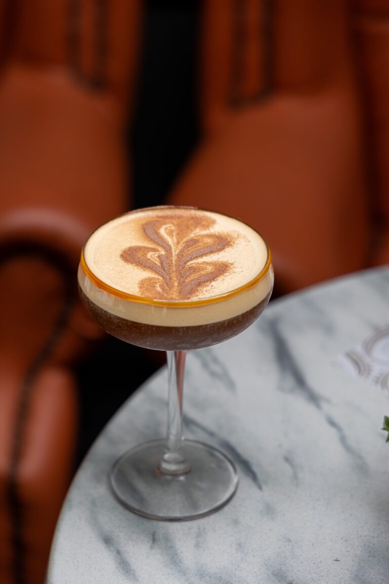 Creamy cocktail with leaf latte art in coupe glass