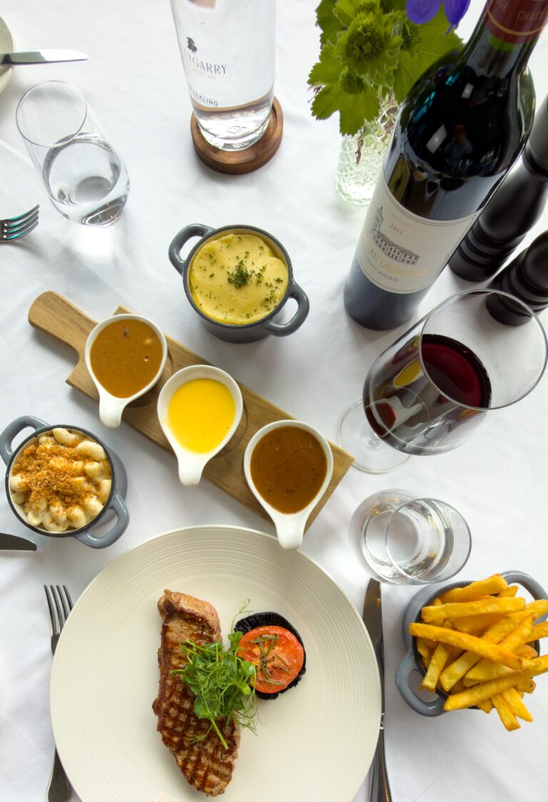Steak dinner with chips, sauces and red wine